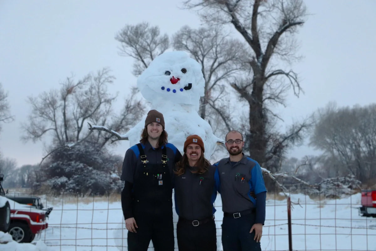 The Green Light Automotive crew in front of a giant snowman outside the shop