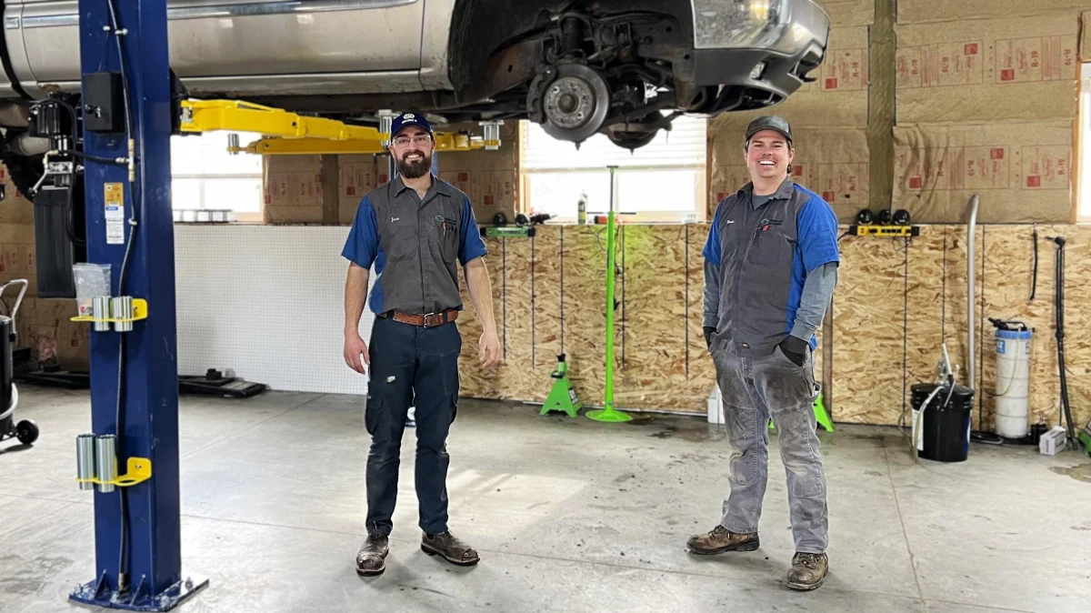 Green Light Automotive technicians standing under a truck on a lift